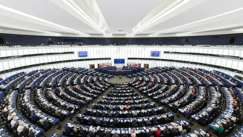 Vista panorámica del hemiciclo del Parlamento Europeo en Estrasburgo, con los escaños ocupados y la bandera de la Unión Europea al fondo.