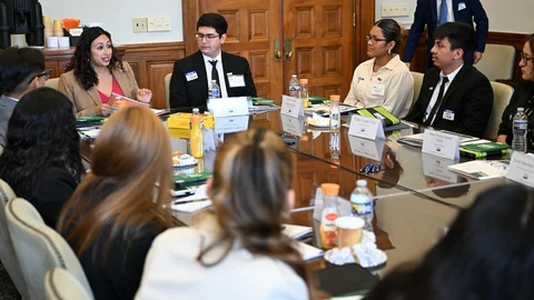 Una mujer habla con varios jóvenes sentados alrededor de una mesa durante una sesión de orientación de prácticas.